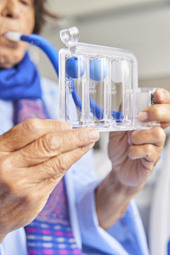 spirometer for breathing exercises. senior woman in hospital room